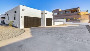 Una casa moderna de dos pisos con garaje, entrada para vehículos y un jardín con plantas pequeñas.