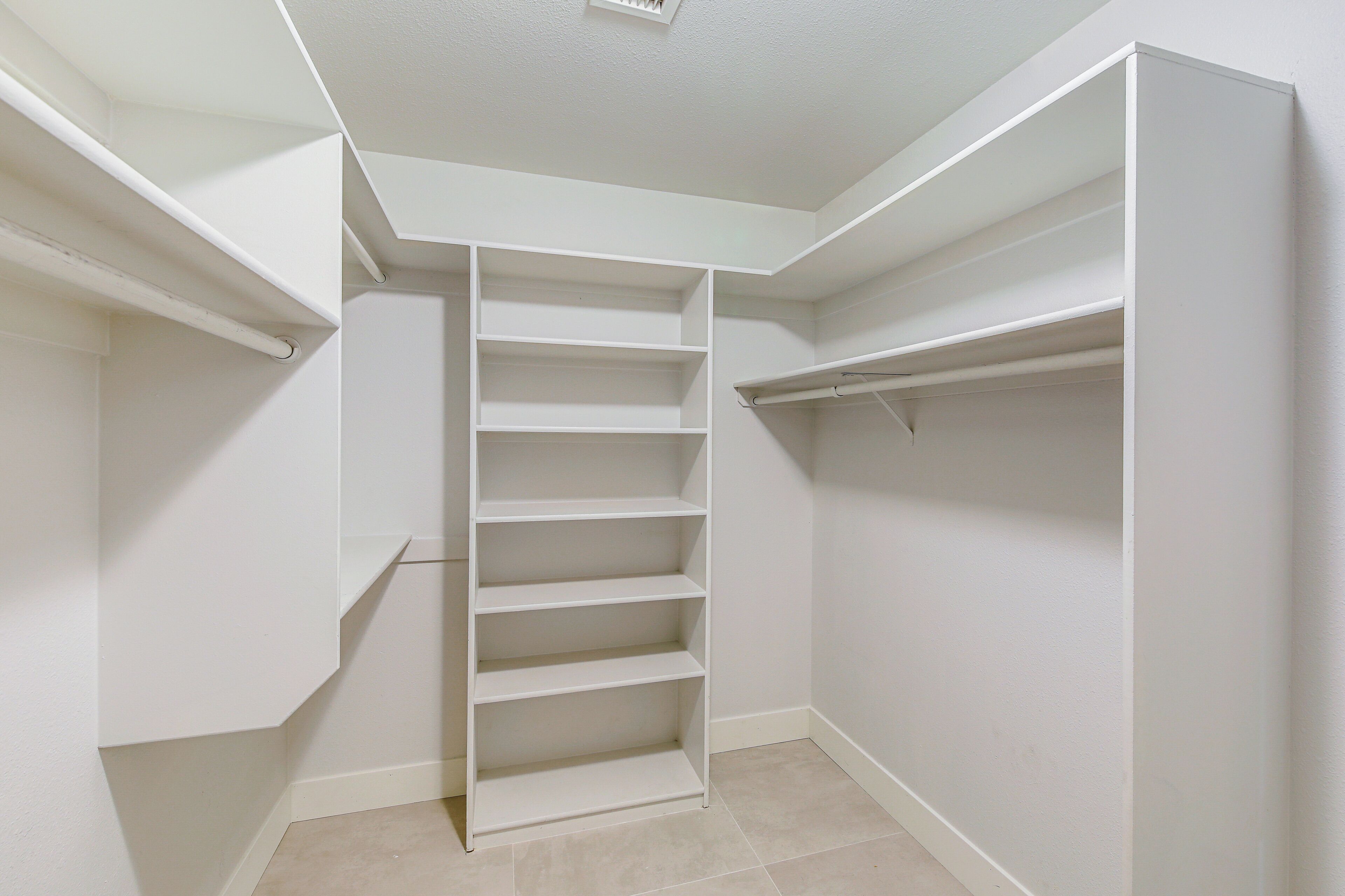 A walk-in closet with multiple shelves and hanging space.