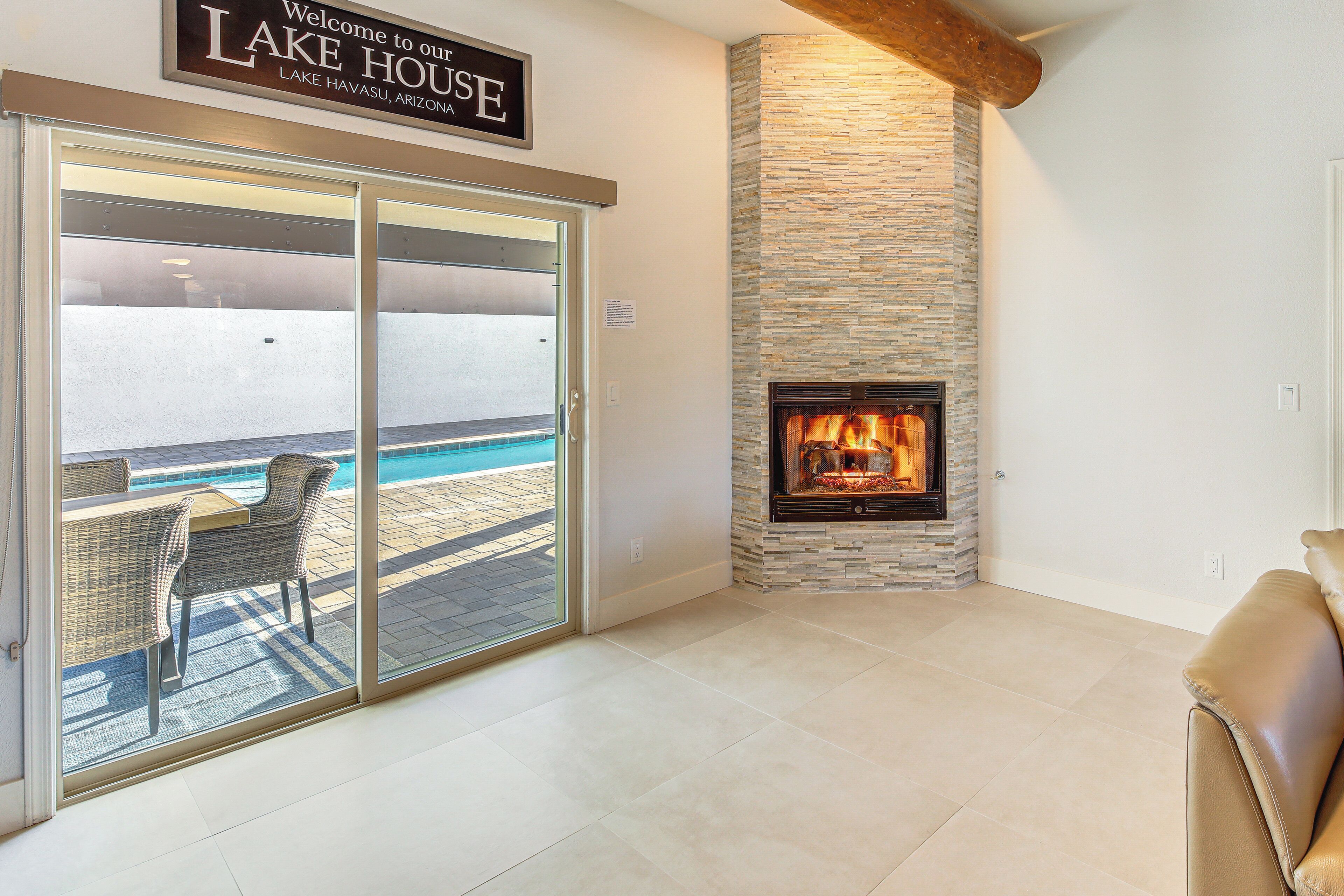 Ein modernes Wohnzimmer mit Kamin, Blick auf einen Pool und einem Schild mit der Aufschrift 'Welcome to our LAKE HOUSE'.