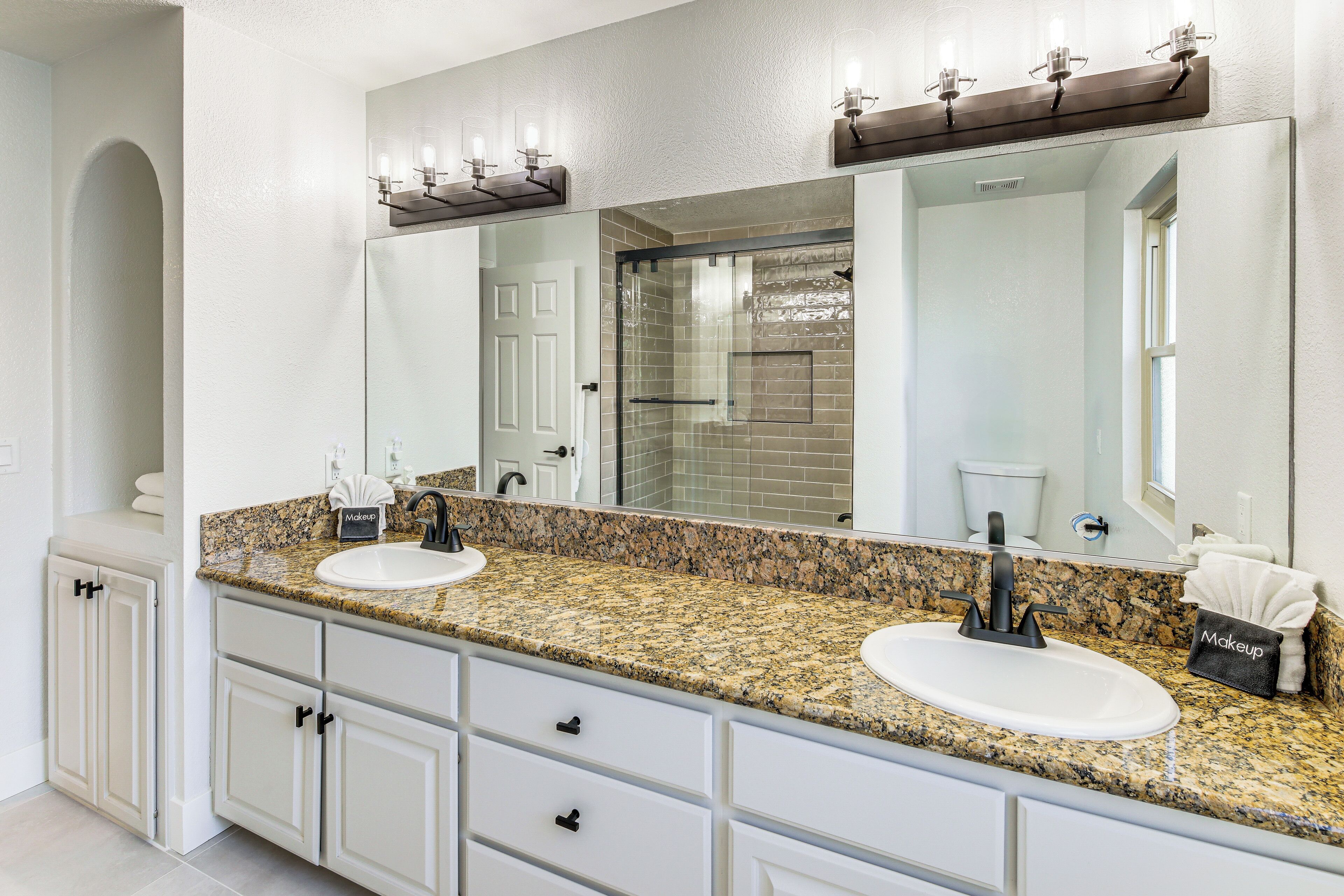 A bathroom with two sinks, a large mirror, and a vanity with drawers.