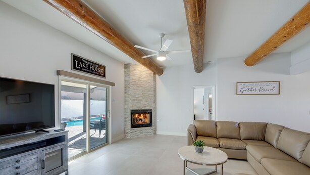 Una sala moderna con chimenea, un sofá de cuero, un televisor y un ventilador de techo.