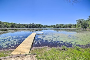 A wooden dock extending into a calm lake surrounded by dense forest. - Lakefront Wisconsin Cottage w/ Dock & Hot Tub! (Pound)