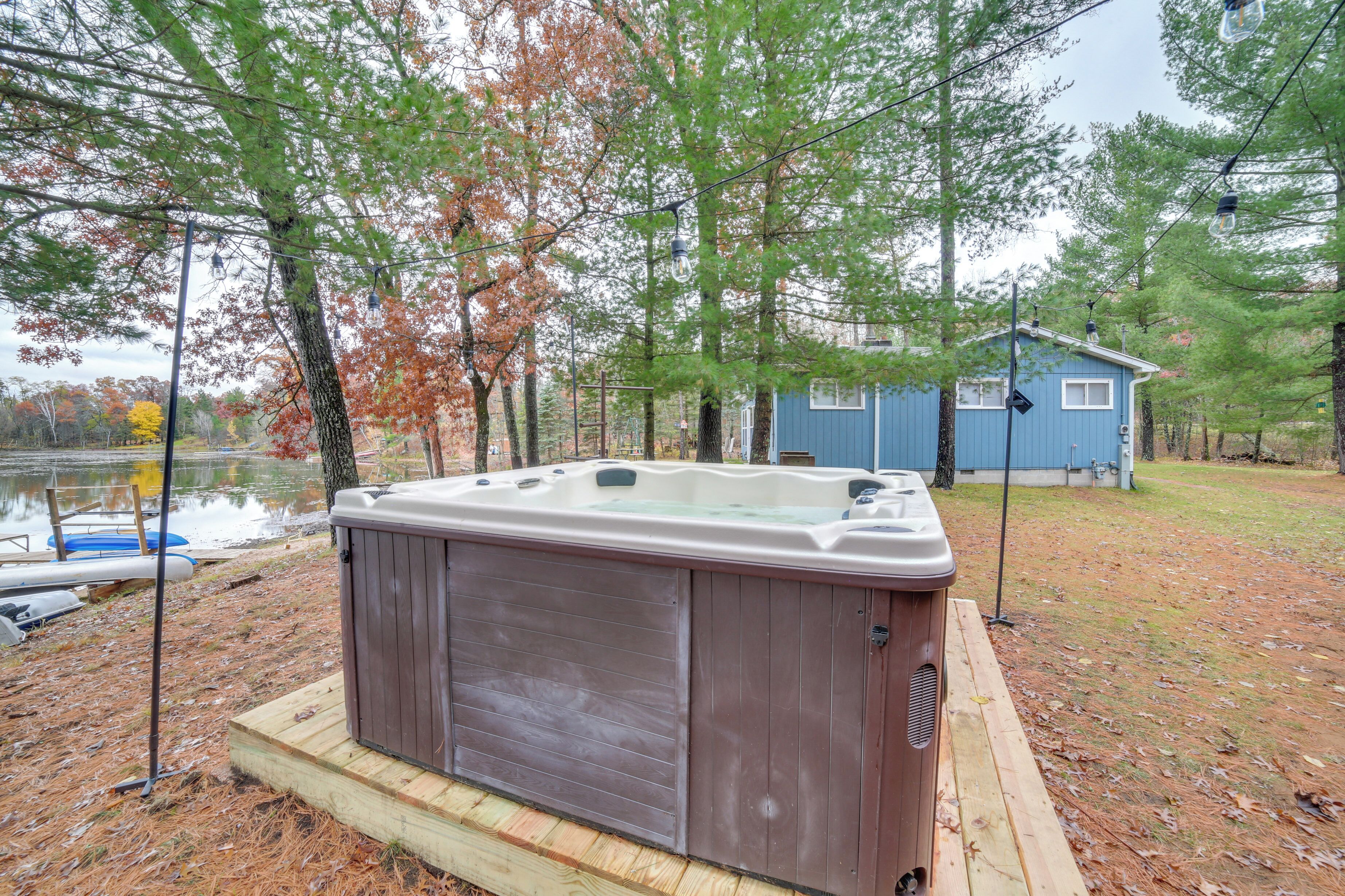 A hot tub on a wooden platform with a house in the background.