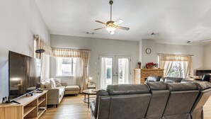 A living room with a sofa, TV, and ceiling fan.