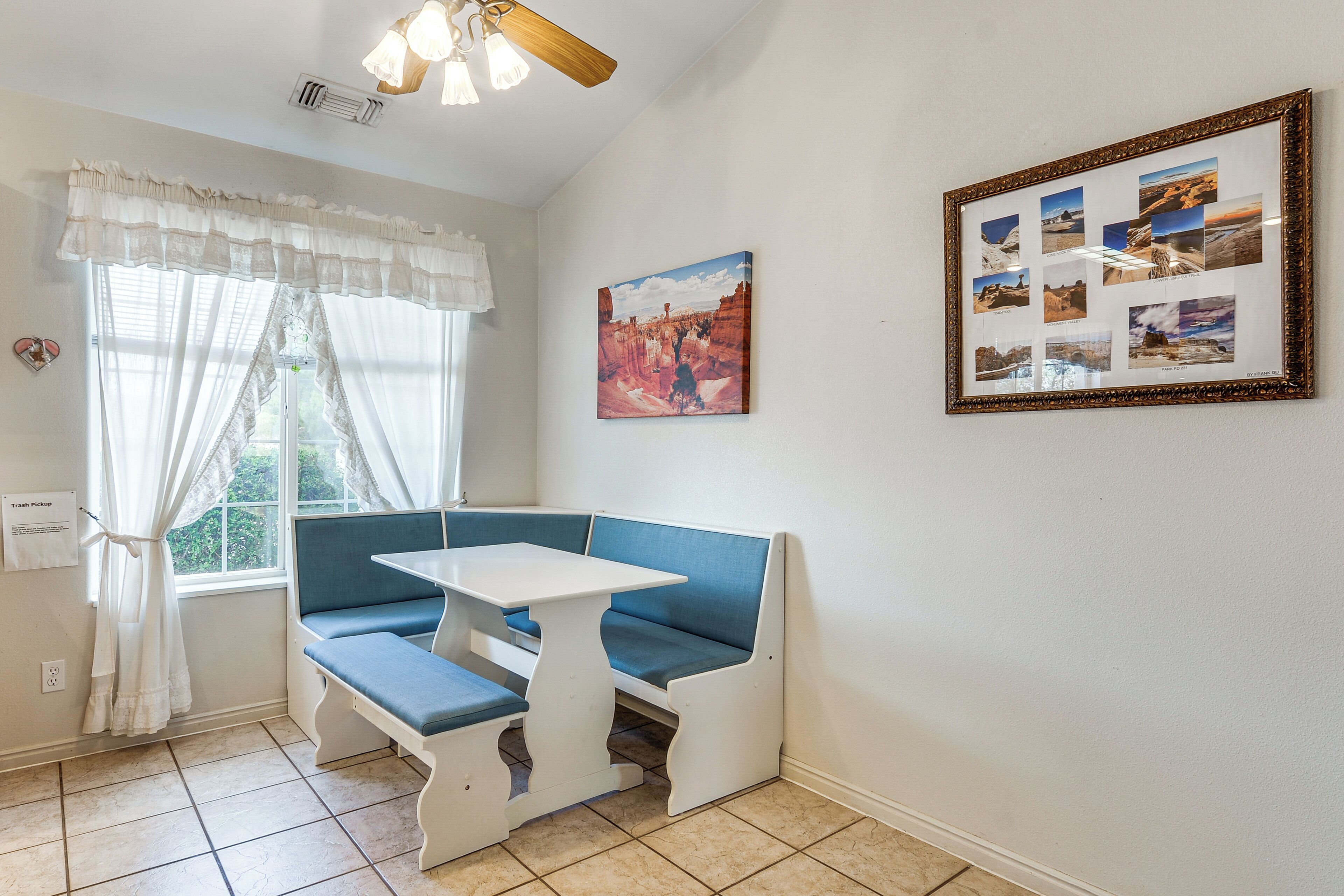 Une pièce avec un banc et une table, une photo encadrée au mur et une fenêtre avec des rideaux.