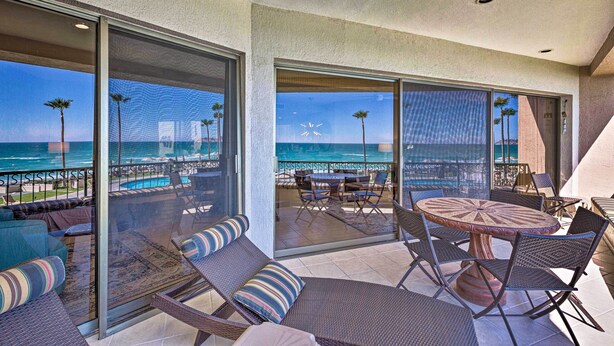 A balcony with a view of the ocean, furnished with wicker chairs and a round table. - Walk to Beach: Oceanfront Rocky Point Condo (Puerto Peñasco)
