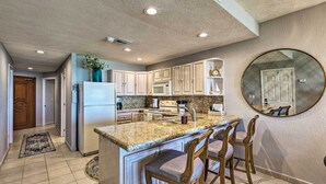 A kitchen with a central island, bar stools, and a large mirror on the wall. - Walk to Beach: Oceanfront Rocky Point Condo (Puerto Peñasco)