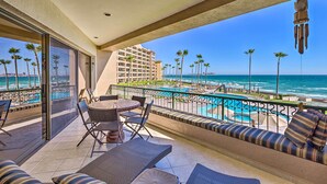 A balcony with a view of the ocean, a pool, and a building in the background. - Walk to Beach: Oceanfront Rocky Point Condo (Puerto Peñasco)