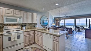 A kitchen with granite countertops, white appliances, and a view of the ocean through large windows. - Walk to Beach: Oceanfront Rocky Point Condo (Puerto Peñasco)