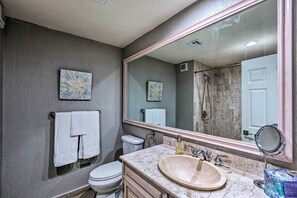 Ein Badezimmer mit Marmorwaschbecken, einem großen Spiegel, einer Toilette und zwei Handtuchhaltern an der Wand.