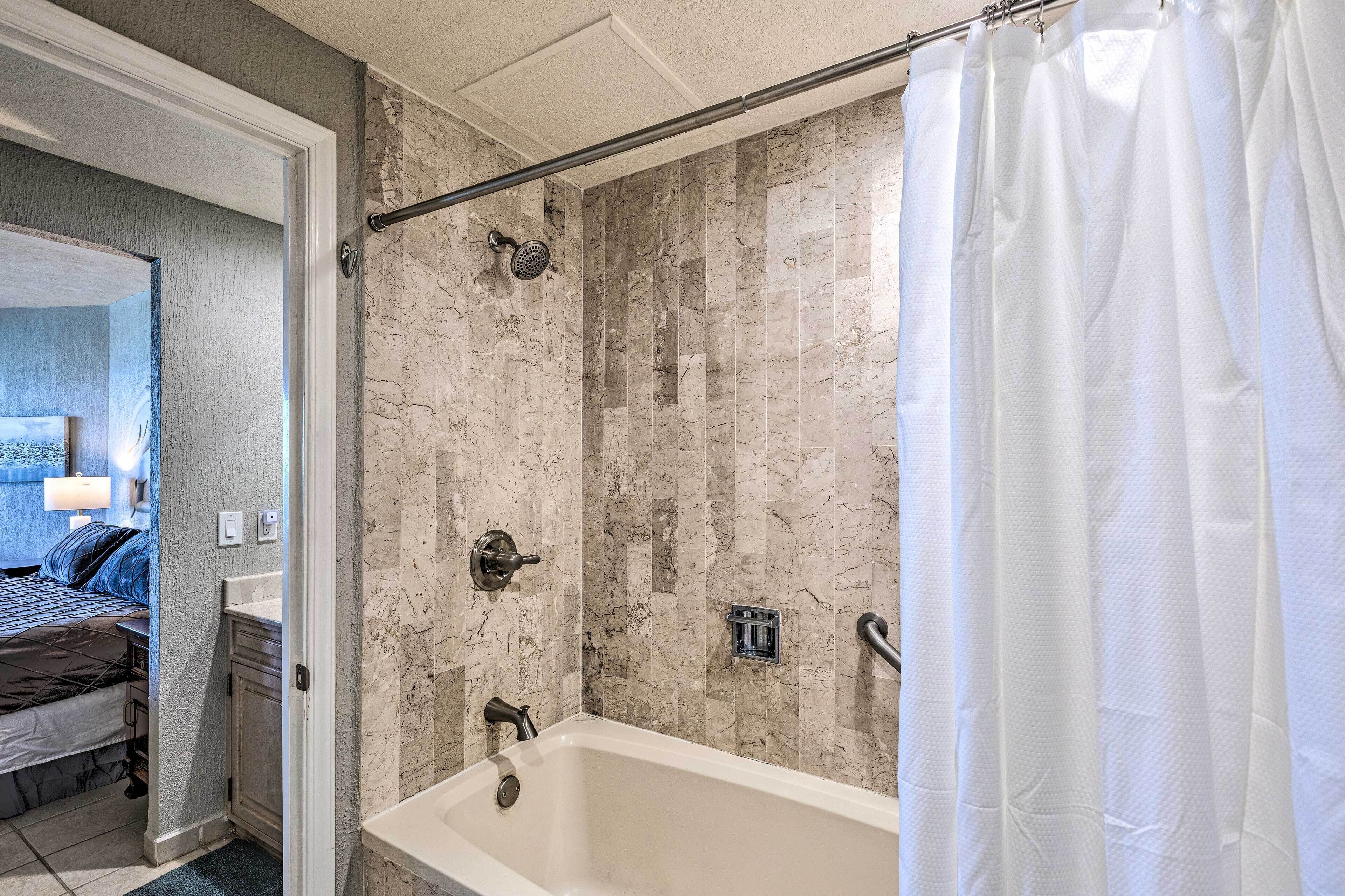 Een badkamer met een bad, douche en een handdoekrek.