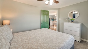 A bedroom with a bed, a dresser, a mirror, a ceiling fan, and a door leading to a dining area. - Omaha Apartment 3 Mi to Cricket Creek Marina! (Omaha)