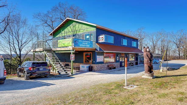 A two-story building with a blue and green exterior, a bear statue in front, and a sign for a bait and tackle shop. - Omaha Apartment 3 Mi to Cricket Creek Marina! (Omaha)