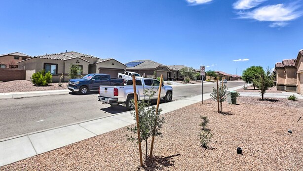 A residential street with houses, a blue truck, and a white truck parked on the side. - Inviting Sahuarita Home < 5 Mi to Lake Park! (Sahuarita)