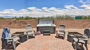 An outdoor patio with four Adirondack chairs, a hot tub, and a brick wall backdrop. - Inviting Sahuarita Home < 5 Mi to Lake Park! (Sahuarita)