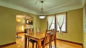 A dining room with a wooden table and chairs, a chandelier, and a window with curtains. - Cozy Duplex: Half Mi to Magic Bag & Woodward Ave! (Ferndale)