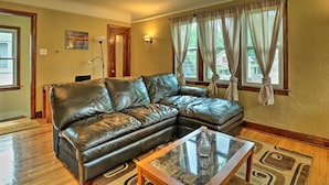 A living room with a leather sectional sofa, a glass coffee table, and a rug. - Cozy Duplex: Half Mi to Magic Bag & Woodward Ave! (Ferndale)