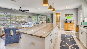 A modern kitchen with a marble countertop, white cabinets, and pendant lighting. - Canalfront Cape Coral Home With Dock & Bbq! (Cape Coral)