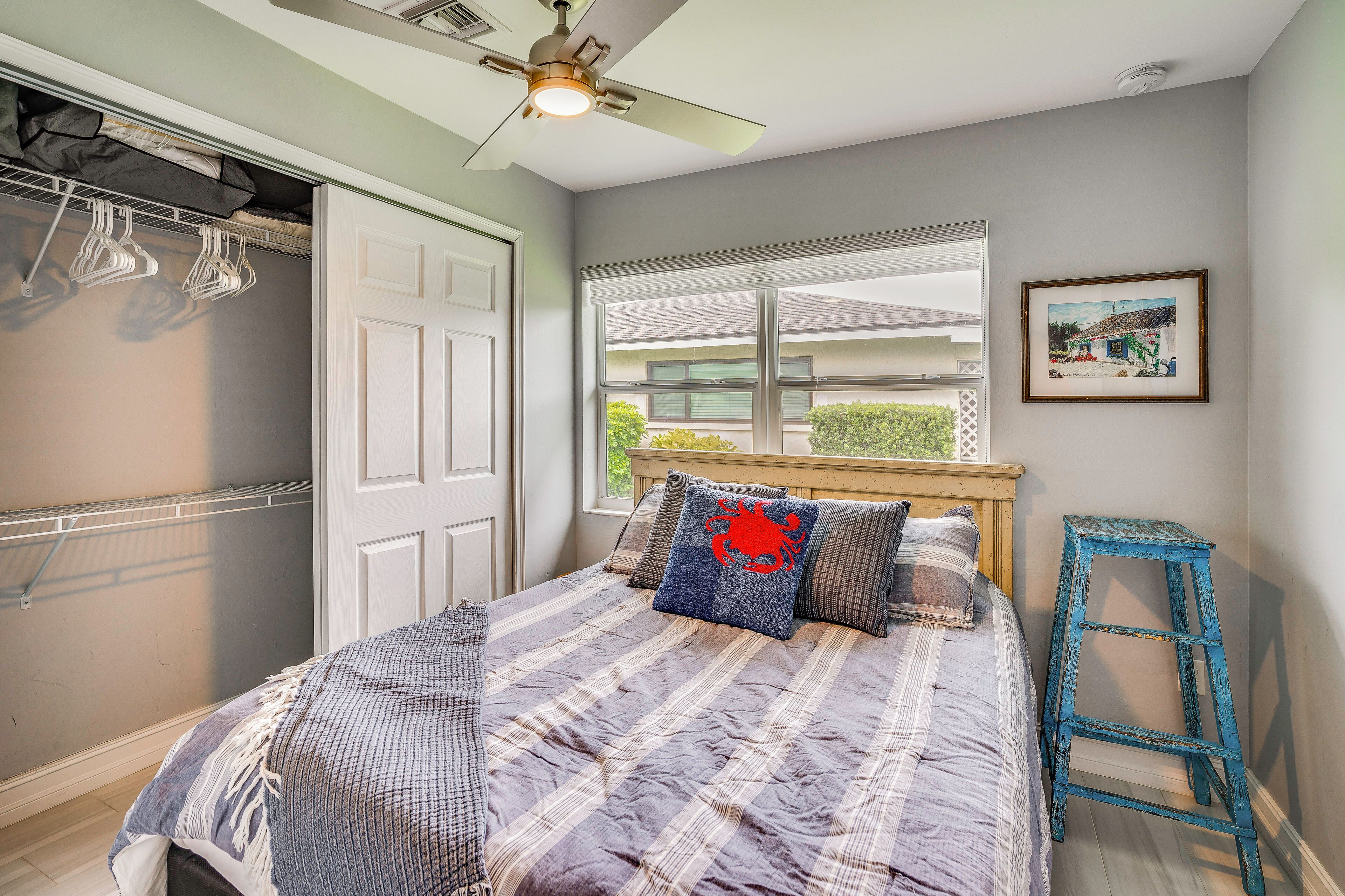 A bedroom with a bed, a ceiling fan, a window, and a door.