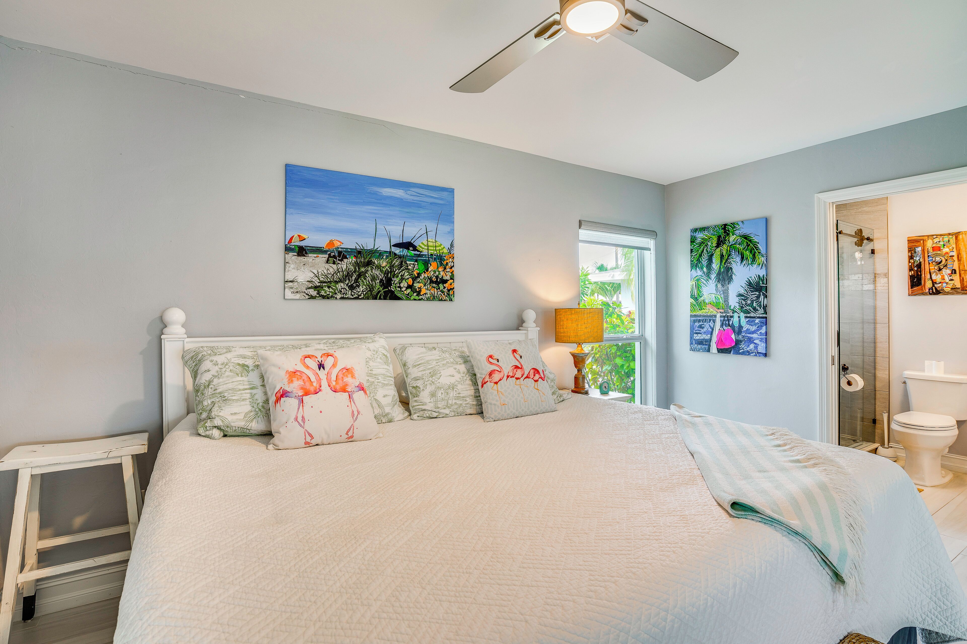 A bedroom with a bed, a ceiling fan, a nightstand, and a window.