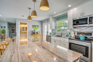 A modern kitchen with a large island, stainless steel appliances, and pendant lighting.