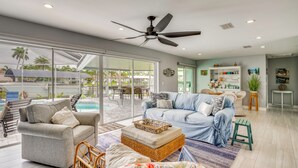 A spacious living area with a large window, a ceiling fan, and a pool view. - Canalfront Cape Coral Home With Dock & Bbq! (Cape Coral)
