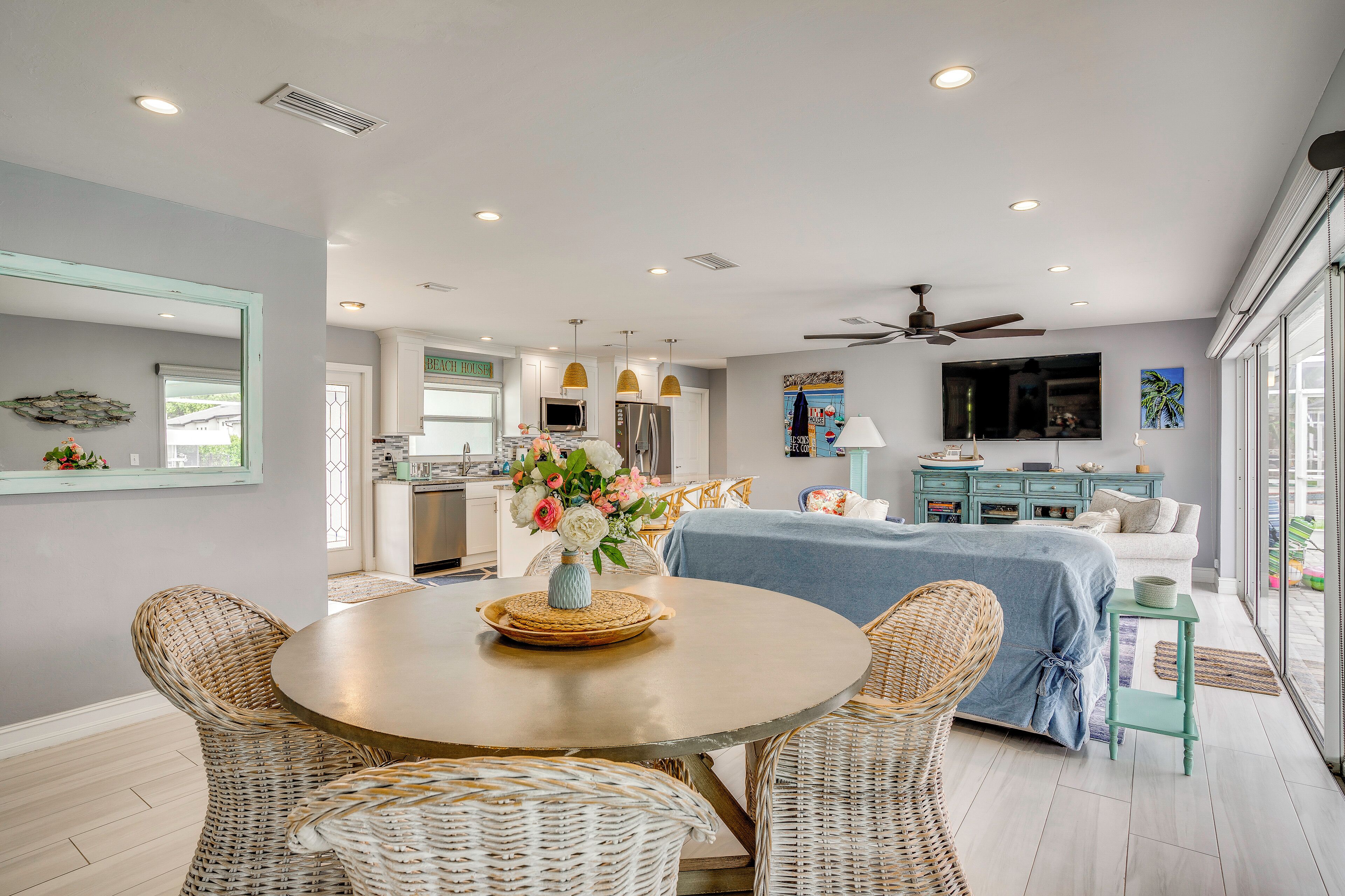 A modern kitchen with a dining area, a bedroom with a large bed and a TV, and a living room with a sofa and a TV.