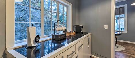 A kitchen with a large window, a coffee maker, and a dish rack.