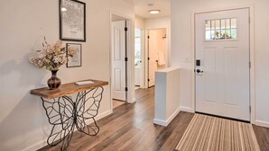 A hallway with a wooden console table, a vase with flowers, and a framed map on the wall. - 2 Mi to State Farm Stadium: Phoenix Retreat (Phoenix)