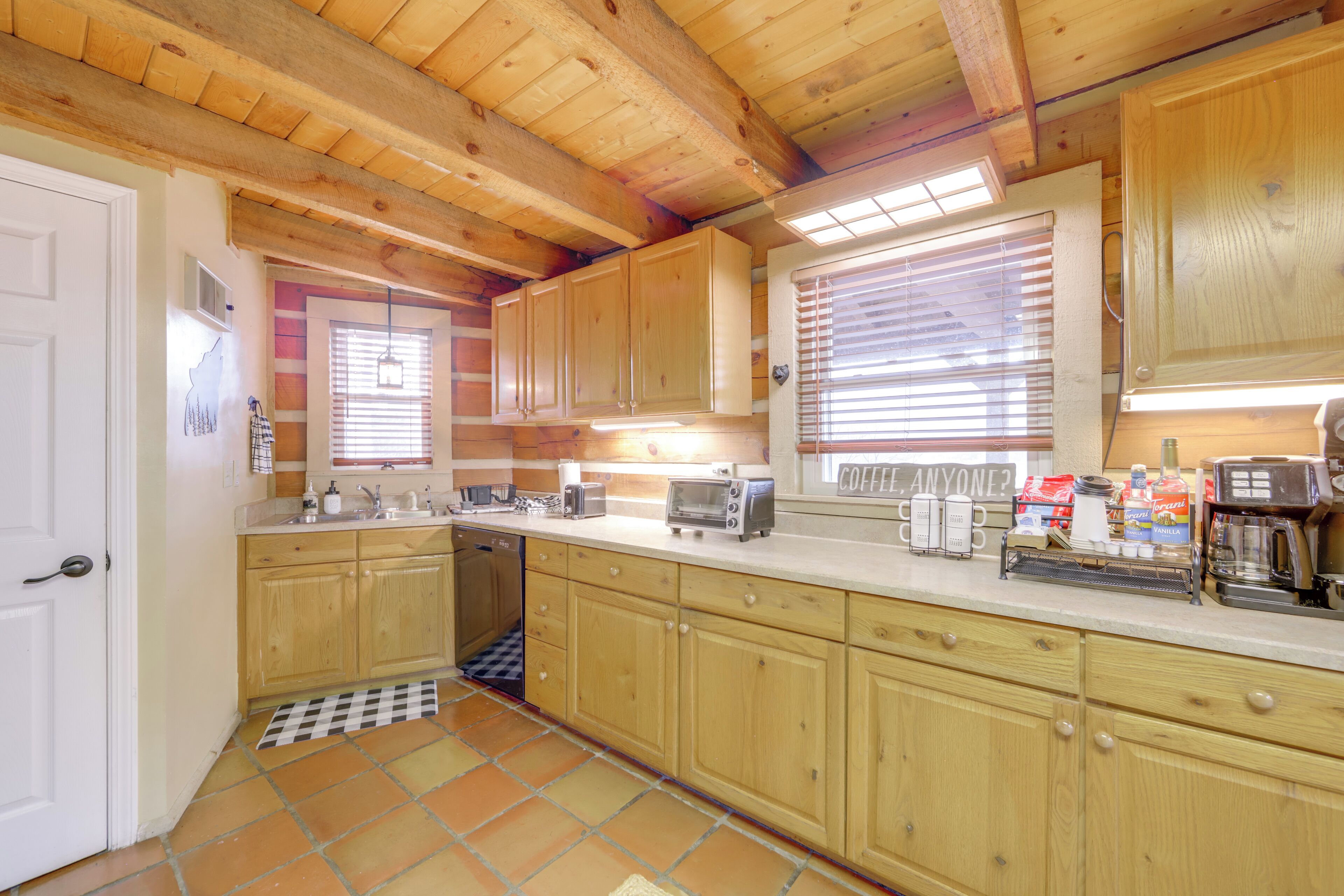 Una cocina con armarios de madera, lavavajillas, cafetera y suelo a cuadros.