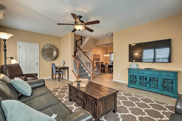 Relax in this inviting living room with a comfortable sofa, flat-screen TV, and decorative sunburst mirror.