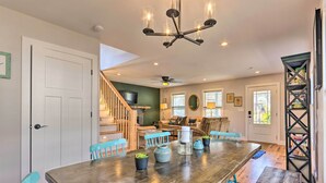 A spacious dining area with a large wooden table, blue chairs, and a chandelier. - Downtown Brevard Retreat With Fire Pit & Deck! (Brevard)