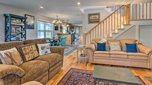A spacious living area with a beige sofa, a brown couch, and a wooden staircase. - Downtown Brevard Retreat With Fire Pit & Deck! (Brevard)