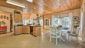 A spacious kitchen with wooden cabinets, a central island, and a dining area with white chairs and a table. - < 2 Mi to Hikes & Shops: Show Low Home w/ Deck (Show Low)