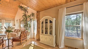 A cozy living room with a wooden ceiling, a large window with curtains, a wooden cabinet, and a comfortable seating area. - < 2 Mi to Hikes & Shops: Show Low Home w/ Deck (Show Low)