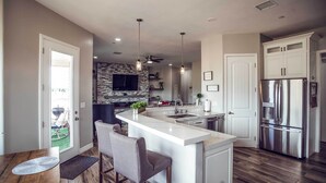 A modern kitchen with a central island, bar stools, a built-in oven, and a stainless steel refrigerator. - Vistas Bonitas Home w/ Patio: 7 Mi to Snowbowl! (Flagstaff)