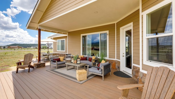 A covered outdoor deck with seating and a table, large windows, and a view of the landscape. - Vistas Bonitas Home w/ Patio: 7 Mi to Snowbowl! (Flagstaff)