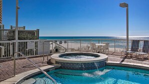 A rooftop pool with a view of the ocean, surrounded by a white fence and a few lounge chairs. - Gulf Coast Getaway w/ Balcony & Resort Amenities! (Panama City Beach)