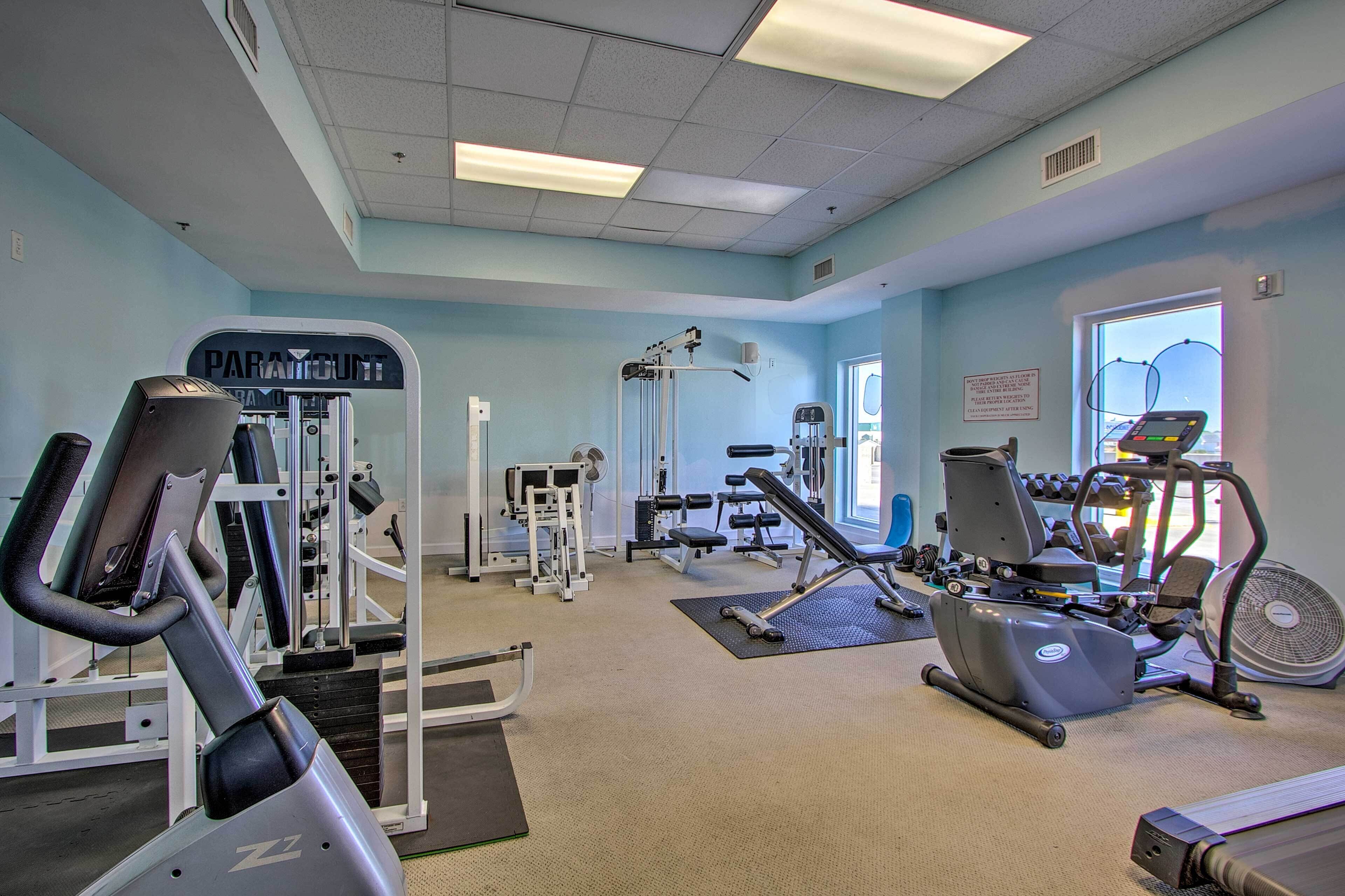 A gym with cardio machines, weight training equipment, and a large window.