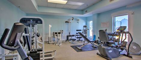 A gym with cardio machines, weight training equipment, and a large window.