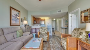 A living room with a sofa, chairs, a coffee table, and a kitchen in the background. - Gulf Coast Getaway w/ Balcony & Resort Amenities! (Panama City Beach)