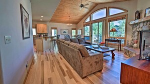 A spacious living room with a wooden ceiling, a large sofa, a coffee table, and a stone fireplace. - Mountain Home With Decks, Walk to Gondola (Steamboat Springs)