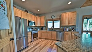 A modern kitchen with wooden cabinets, stainless steel appliances, and a granite countertop. - Mountain Home With Decks, Walk to Gondola (Steamboat Springs)