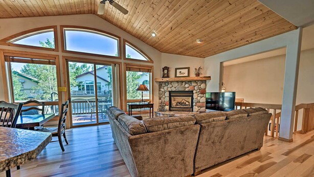A spacious living area with a large sofa, a fireplace, and a television. - Mountain Home With Decks, Walk to Gondola (Steamboat Springs)