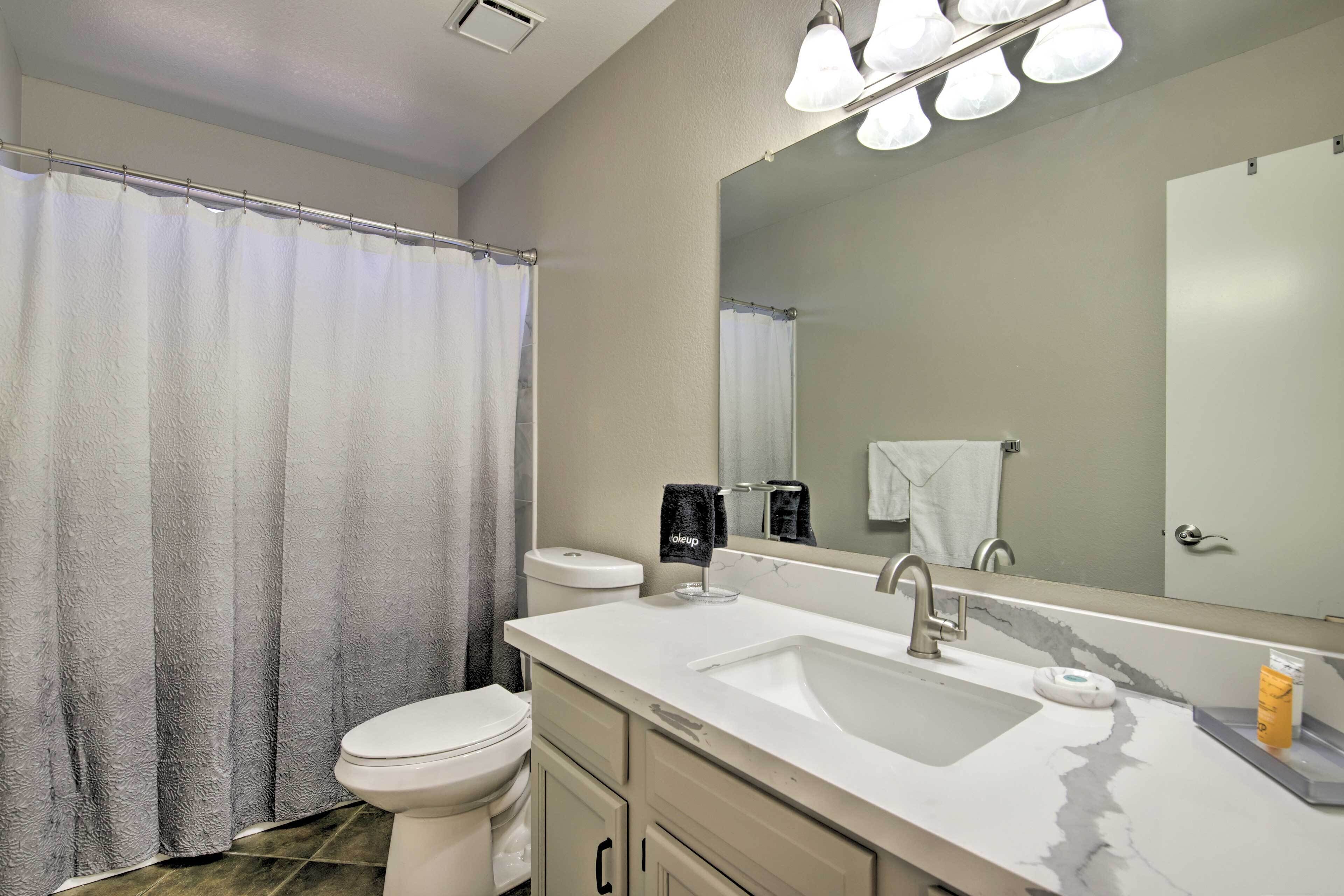 A modern bathroom with a toilet, sink, and mirror.