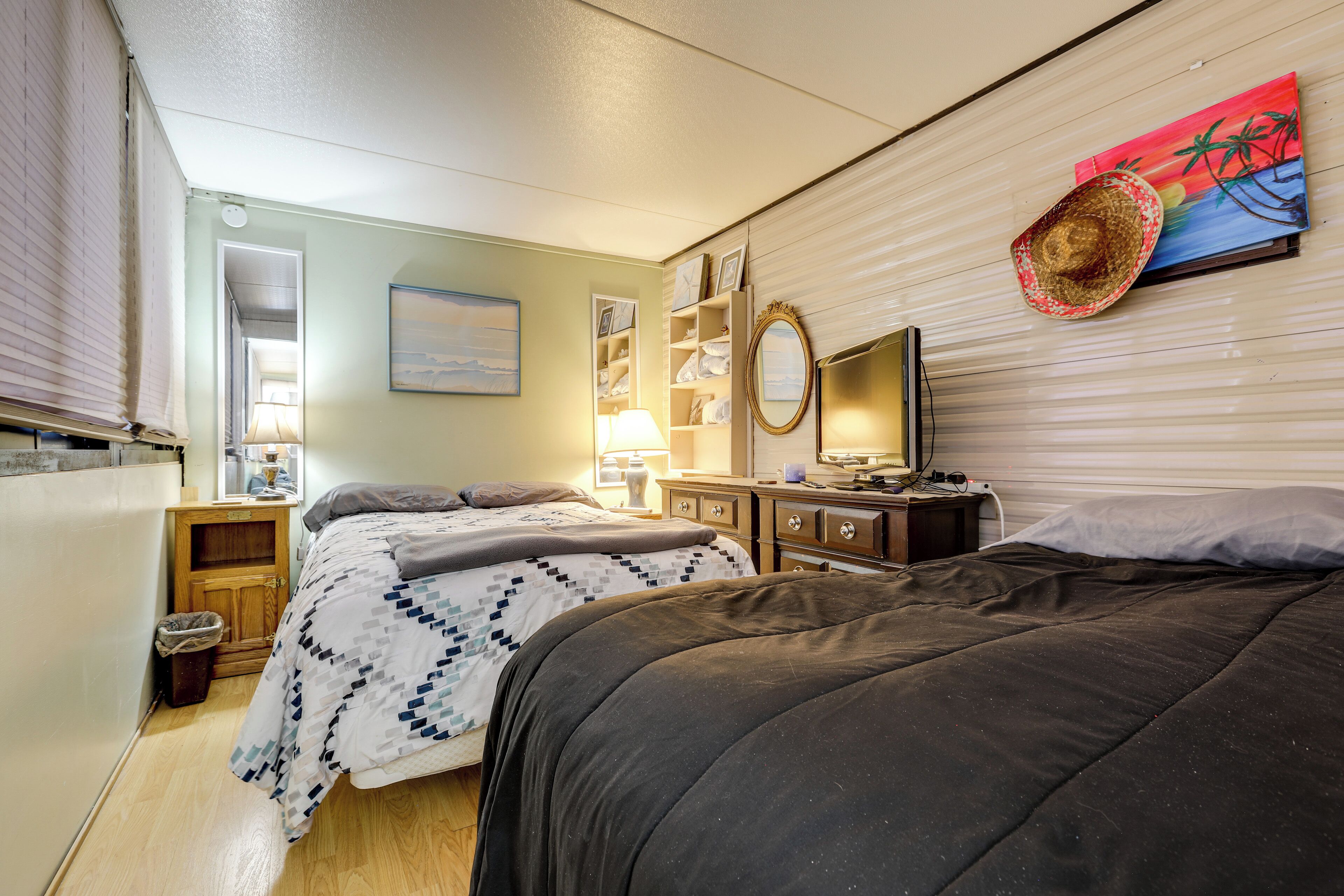 A bedroom with two beds, a dresser, a mirror, and a painting on the wall.