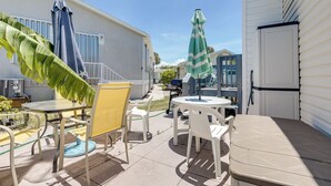 Un patio con mobiliario exterior, incluyendo sillas, mesas y sombrillas.