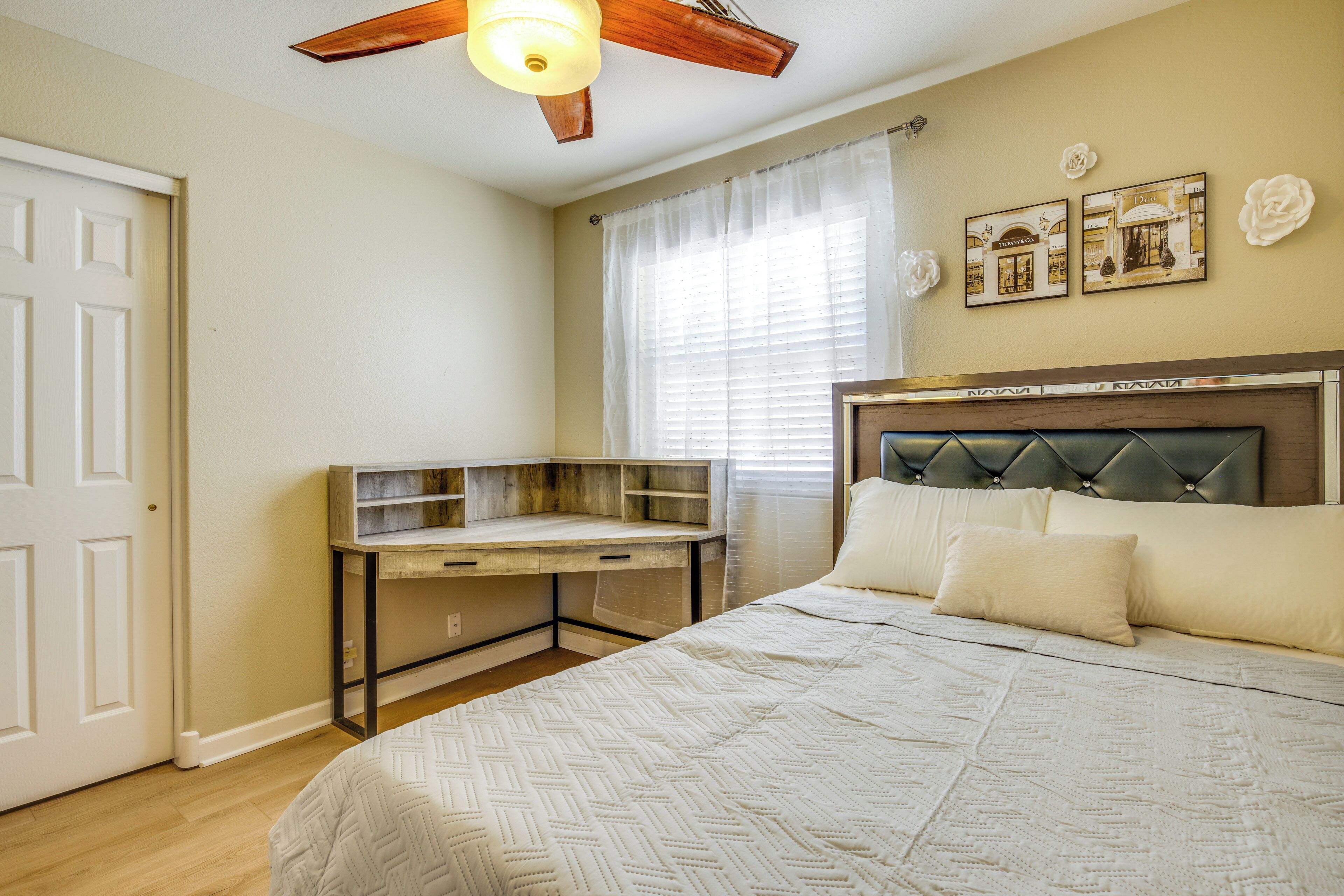 A bedroom with a bed, a desk, and a ceiling fan.