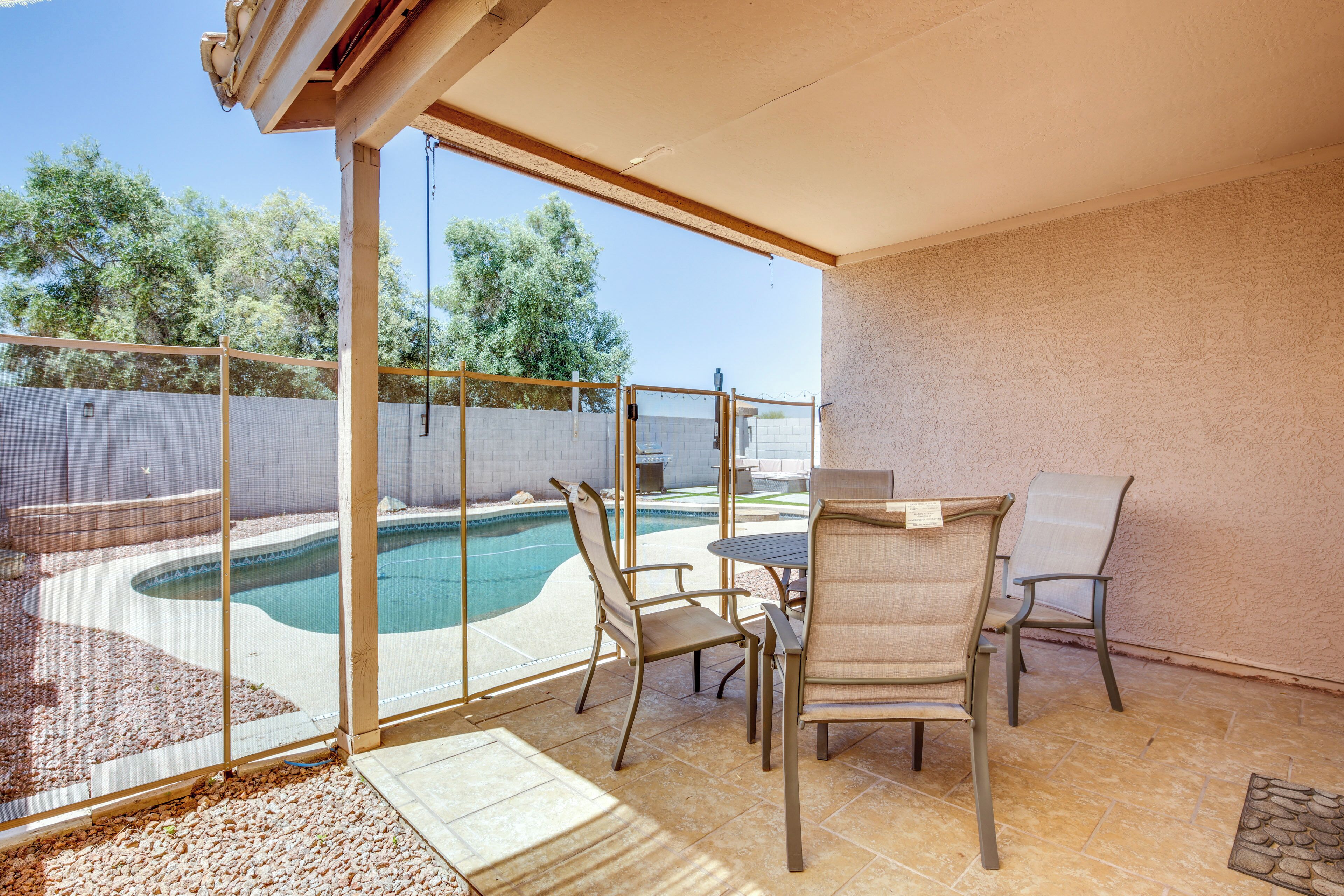 A covered patio with a pool, outdoor seating, and a view of the surrounding area.