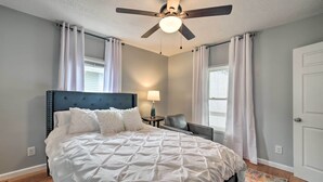 Ein Schlafzimmer mit einem großen Bett, einem Deckenventilator und einem Nachttisch mit Lampe.